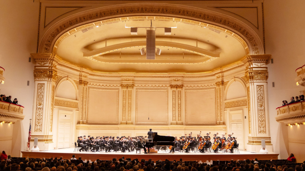 A grand view of the Brown orchestra performing on stage at Carnegie Hall. 