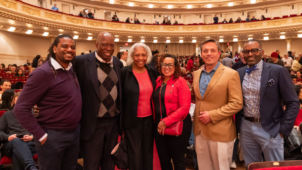 A group of alumni standing together and smiling  inside Carnegie Hall. 
