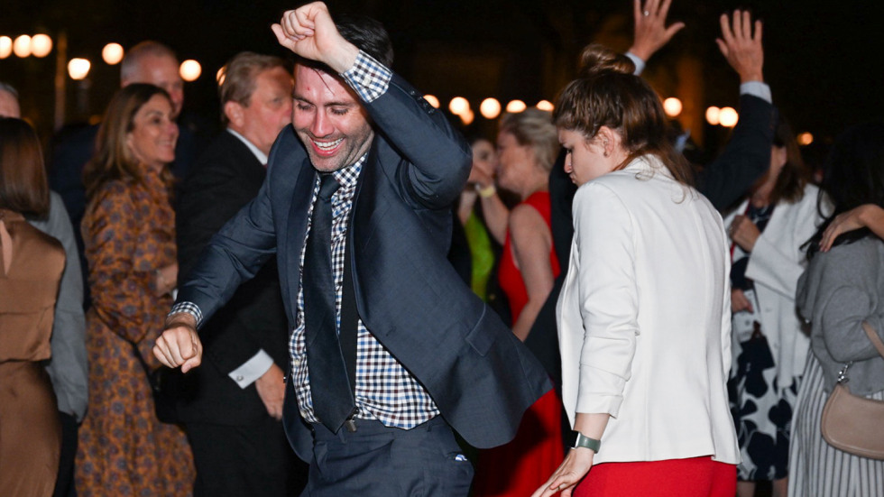 Brown alums dancing with their arms in the air