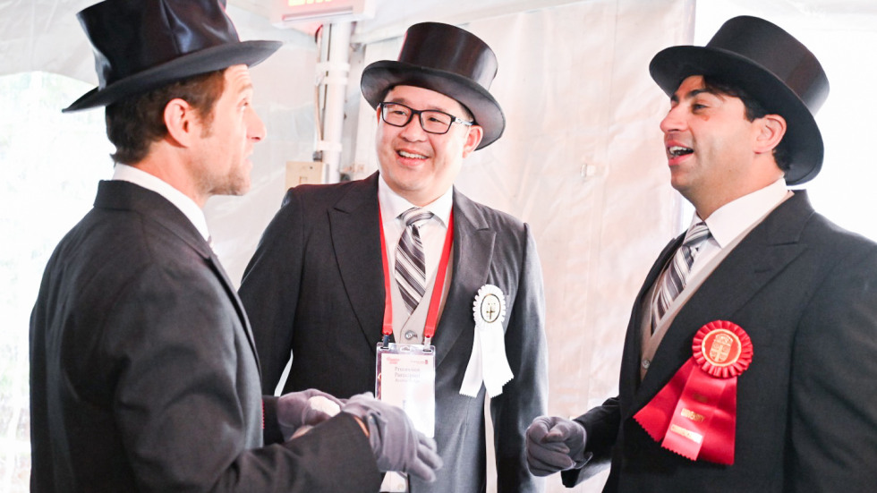 Three alums in formal attire getting ready for the Procession