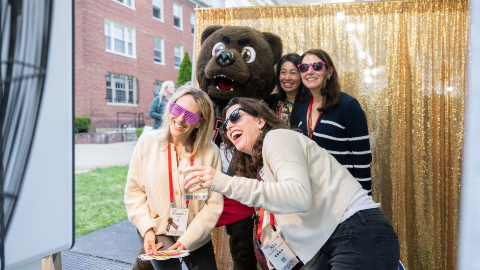 Brown alums celebrating at a class event while taking a picture with the Bruno mascot