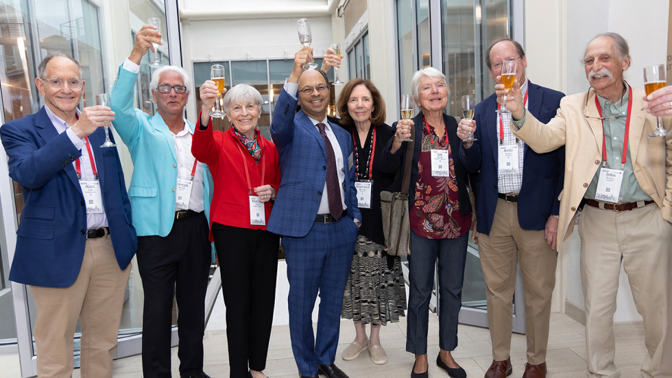 A group from the Class of '76 holding glasses in a cheers.