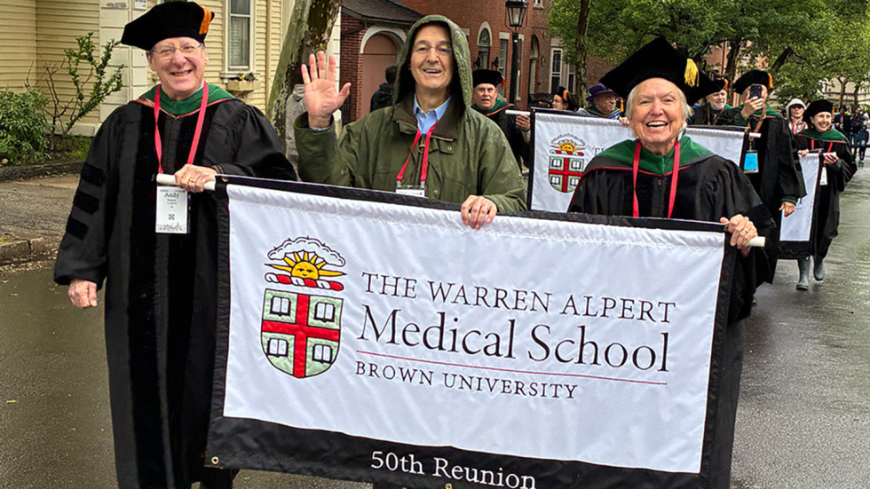 Three members of the MD Class of 1976 holding the 50th Reunion banner in the Procession.