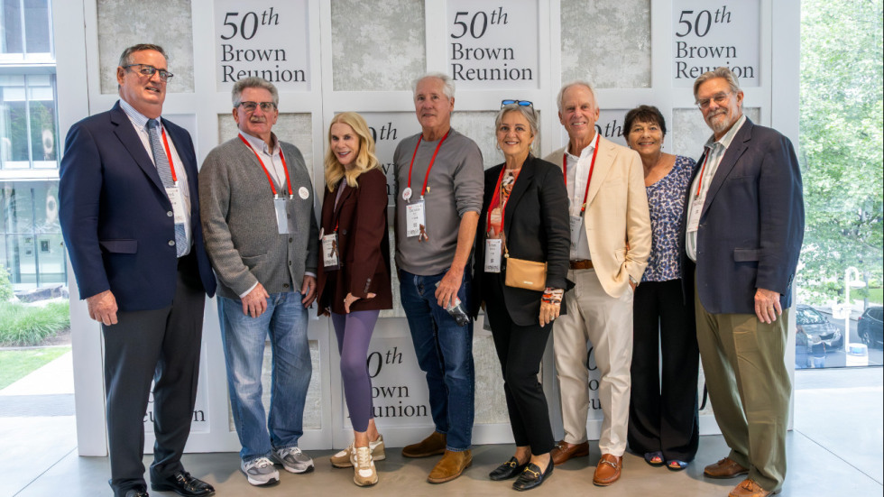 alums pose in front of 50th Reunion signage