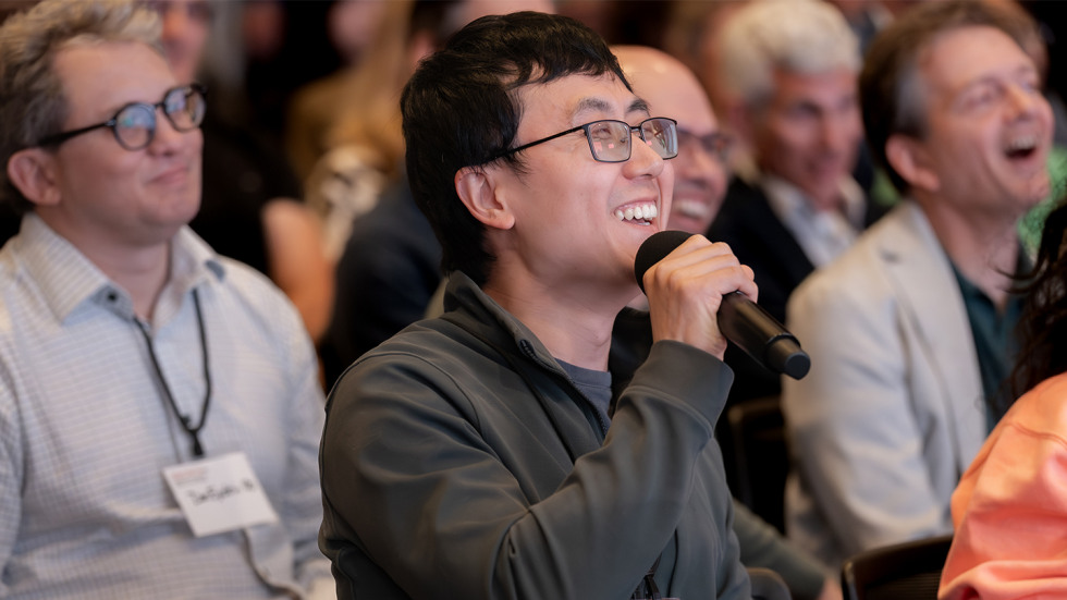 An audience member holding a microphone and laughing, after asking a question.