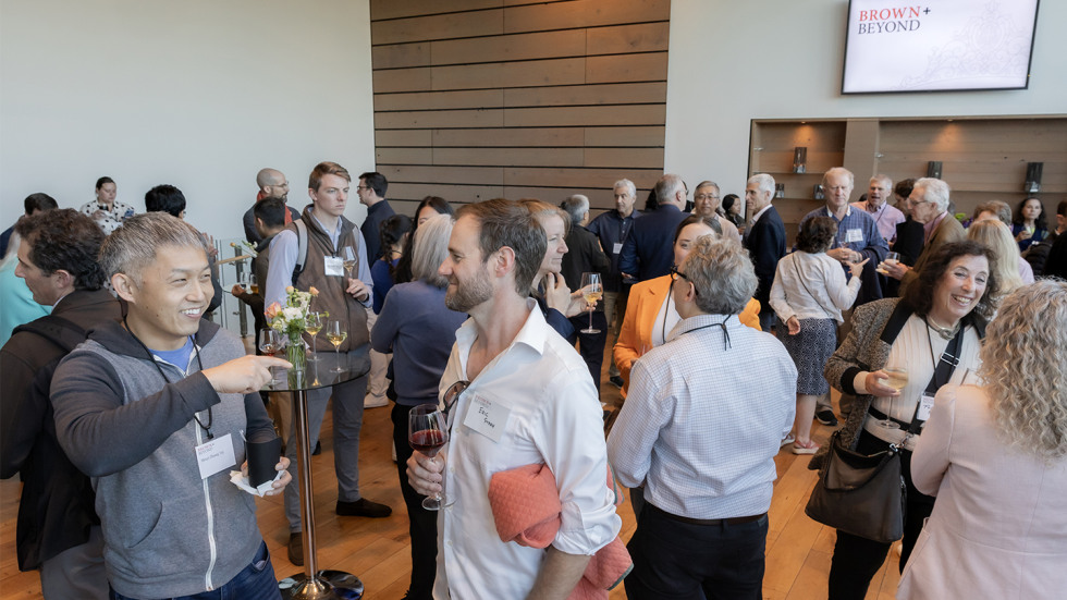 A crowd of attendees mingling and talking in a reception area.