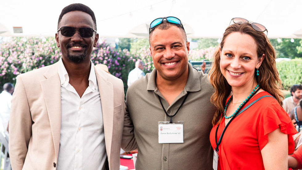 Three people standing together, smiling at the camera. 