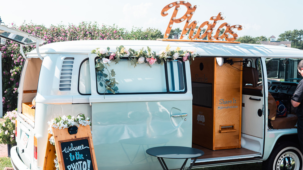 A light blue vintage VW bus with a large sign that says "Photos" on the top.