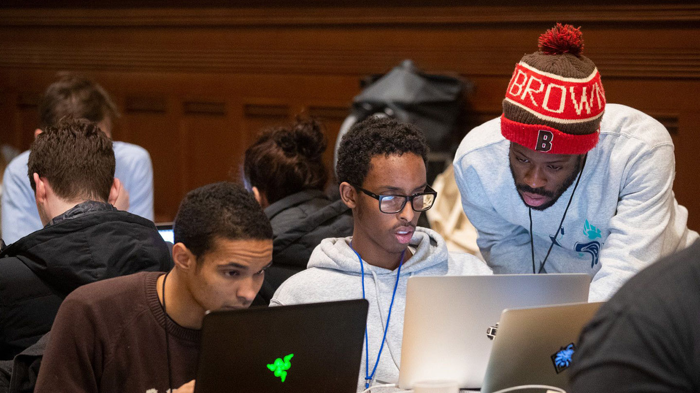 Brown students looking over a laptop computer