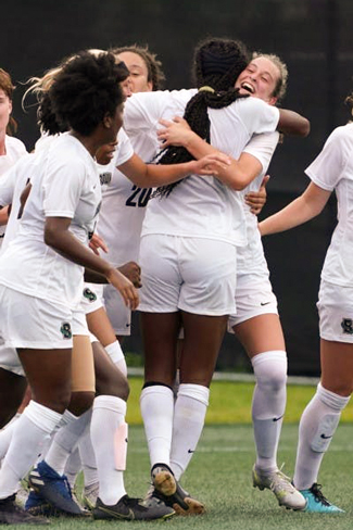 members of the Brown's women's soccer team hugging and celebrating on the field