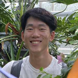 Eric Cho standing in a greenhouse surrounded by plants