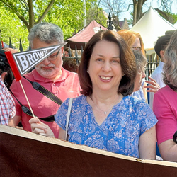 Suzanne Auclair poses in front of a Brown class banner while waving a Brown pennant.
