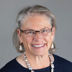 Nora Burgess posing for a photo against a gray backdrop.